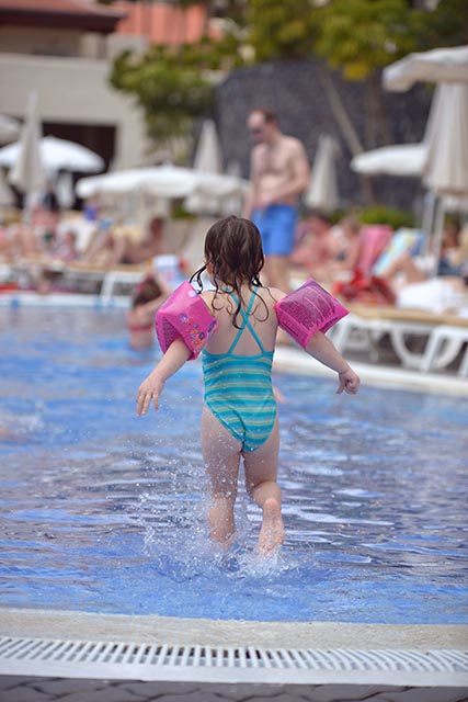 Child splashing in a pool at a family friendly all inclusive resort